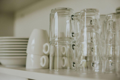 Tazas de cristal apiladas y platos en un estante en la tiny house Cosy house de Camping Si-Es-An, Países Bajos.