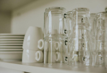 Tazas de cristal apiladas y platos en un estante en la tiny house Cosy house de Camping Si-Es-An, Países Bajos.
