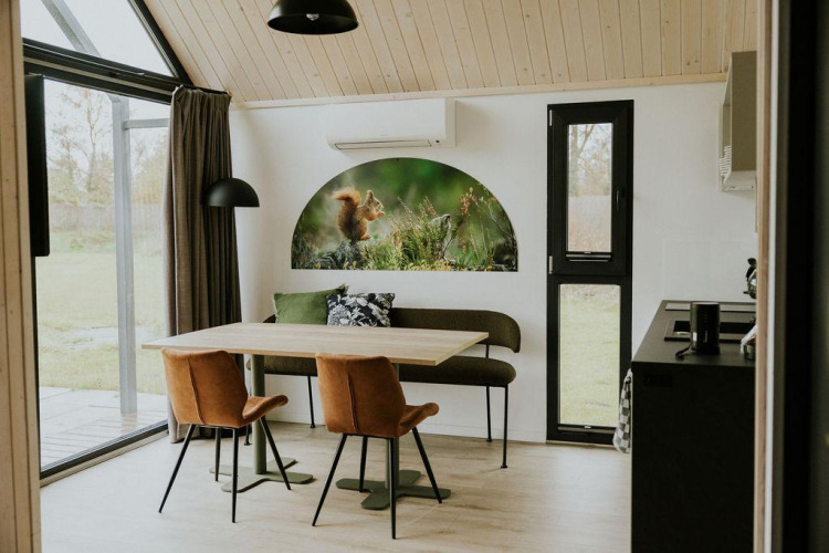 Interior de una tiny house en Camping Si-Es-An, con mesa de comedor, ventanales y arte de ardilla.