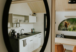Reflejo en espejo de cocina y comedor moderno en una tiny house en Camping Si-Es-An, Países Bajos.