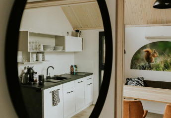 Moderne minikøkken og spiseområde reflekteres i et spejl i et hyggeligt tiny house i Camping Si-Es-An, Holland.