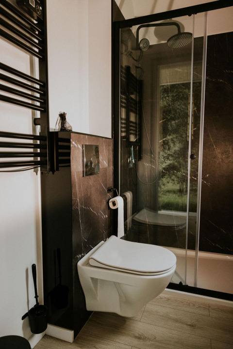 Baño moderno con inodoro suspendido y ducha negra en una tiny house de Camping Si-Es-An, Países Bajos.
