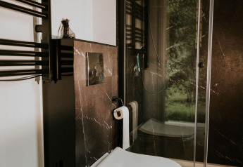 Salle de bain moderne avec WC suspendu et douche noire dans un tiny house au Camping Si-Es-An, Pays-Bas.