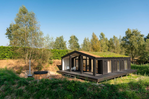 Tiny house avec toit végétalisé et bain à remous extérieur, entourée de nature à Wilsumer Berge, Allemagne.