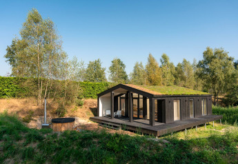 Et lille hus med græs på taget og udendørs hottub i naturskønne omgivelser ved Wilsumer Berge i Tyskland.