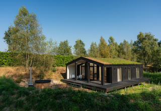 Et lille hus med græs på taget og udendørs hottub i naturskønne omgivelser ved Wilsumer Berge i Tyskland.