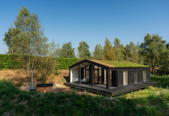Et lille hus med græs på taget og udendørs hottub i naturskønne omgivelser ved Wilsumer Berge i Tyskland.