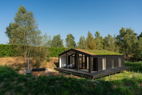 Tiny house with a green roof and outdoor hot tub in scenic nature at Wilsumer Berge, Germany.