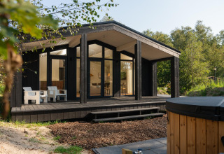 Tiny house ved Wilsumer Berge i Tyskland, med moderne sort facade, terrasse og udendørs varmtvandsbad.