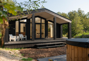 Tiny house ved Wilsumer Berge i Tyskland, med moderne sort facade, terrasse og udendørs varmtvandsbad.