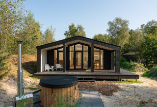 Modern tiny house met houten terras en hottub bij Wilsumer Berge in Duitsland, omringd door natuur.