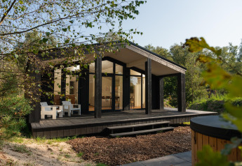 Klein zwart houten huisje met veranda en hottub in de natuur, Hills met Hot tub bij Wilsumer Berge, Duitsland.