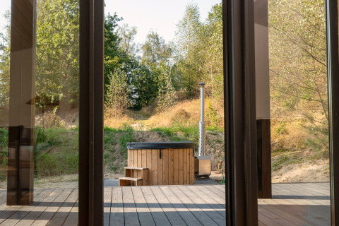 Vue depuis une tiny house à Wilsumer Berge, Allemagne, avec bain à remous en bois et nature environnante.