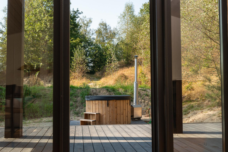 View from a tiny house at Wilsumer Berge, Germany, featuring a wooden hot tub and surrounding nature.