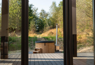 Blick aus einem Tiny House in Wilsumer Berge, Deutschland, mit Hot Tub und bewaldeter Hügellandschaft.