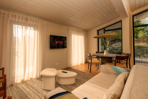 Salon d'une tiny house à Wilsumer Berge, Allemagne, avec canapé, Netflix et coin repas baigné de lumière.