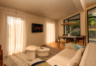 Salon d'une tiny house à Wilsumer Berge, Allemagne, avec canapé, Netflix et coin repas baigné de lumière.