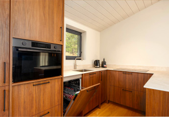 Moderne køkken i et tiny house på Hills med opvaskemaskine, ovn og træskabe, Wilsumer Berge, Tyskland.