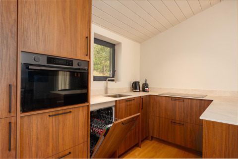 Moderne keuken in het tiny house Hills met houten kasten, open vaatwasser en oven bij Wilsumer Berge, Duitsland.