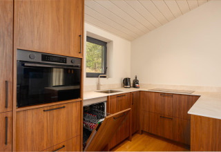 Cucina moderna della tiny house Hills con lavastoviglie aperta e mobili in legno a Wilsumer Berge, Germania.