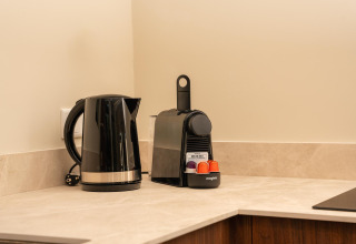 Køkkenhjørne med sort elkedel og kaffemaskine med kapsler i et tiny house ved Wilsumer Berge, Tyskland.