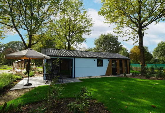 Kids cottage Lodge in Kaatsheuvel, Niederlande, mit grünem Rasen und schattigen Bäumen im Freien.