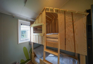 Stapbed met houten frame in Kids cottage in Kaatsheuvel, Nederland, naast een raam met zicht buiten.