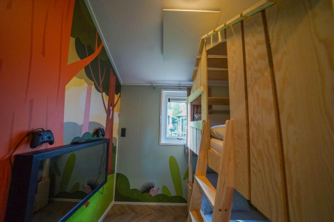 Kinderzimmer im Kids Cottage, Kaatsheuvel, Niederlande mit Etagenbett, Wandbild und Spielkonsole.