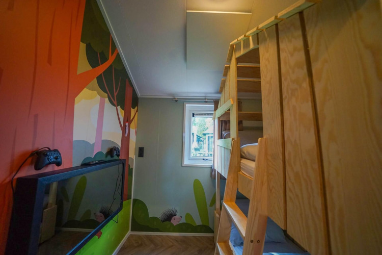 Kids room at Kids cottage in Kaatsheuvel, Netherlands with bunk beds, wall art, and a gaming console.
