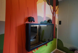 Mural en la pared con televisor y dos mandos en Kids Cottage, Kaatsheuvel, Países Bajos, ambiente infantil.