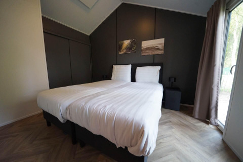 Modernes Schlafzimmer im Kids Cottage in Kaatsheuvel, Niederlande, mit Doppelbett und großen Fenstern.