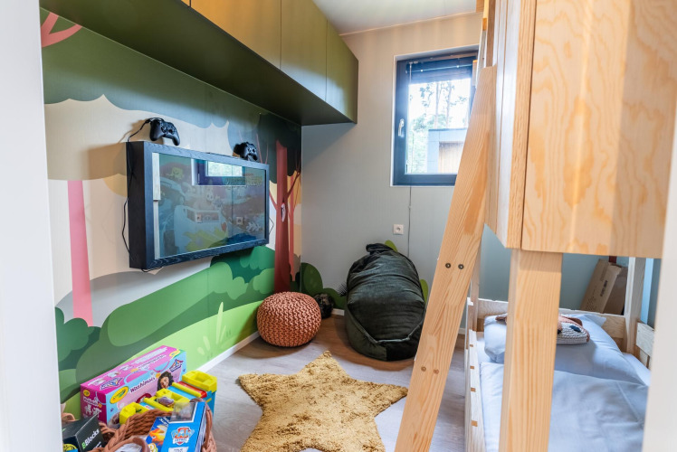 Kids room in Kids cottage at Kaatsheuvel, Netherlands, with bunk bed, toys, TV and forest-themed decor.