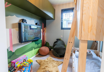 Cameretta nel Kids cottage a Kaatsheuvel, Paesi Bassi, con letto a castello, giochi e decorazioni a tema bosco.