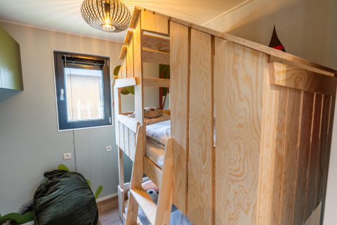 Kinderzimmer mit Holz-Etagenbett, Fenster und moderner Lampe in der Kids Cottage Lodge in Kaatsheuvel, Niederlande.