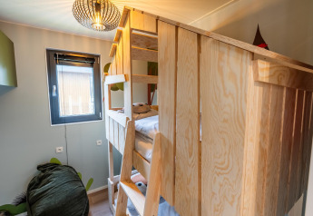 Children’s room with wooden bunk bed, window, and modern lamp at Kids Cottage lodge in Kaatsheuvel, Netherlands.