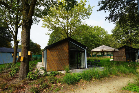 Außenansicht der Kids Cottage Lodge in Kaatsheuvel, Niederlande, mit Garten, Bäumen und Terrasse.
