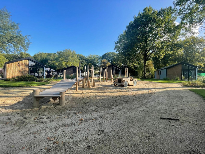 Playground and modern lodges at Kids cottage in Kaatsheuvel, Netherlands, surrounded by greenery.