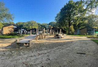 Legeplads og moderne hytter ved Kids cottage i Kaatsheuvel, Holland, omgivet af grønne træer.