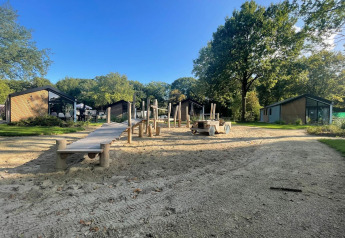 Spielplatz und moderne Lodges bei Kids cottage in Kaatsheuvel, Niederlande, mit viel Grün.