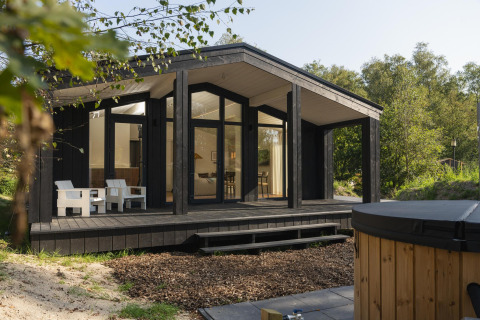 Casa tiny moderna llamada The Hills con amplia terraza de madera, jacuzzi y sauna en entorno natural.