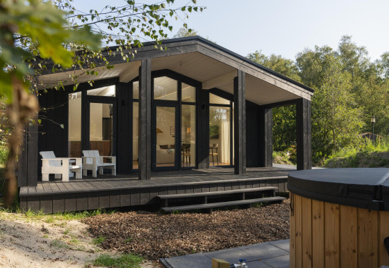 Casa tiny moderna llamada The Hills con amplia terraza de madera, jacuzzi y sauna en entorno natural.