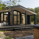 Moderne tiny house kaldet The Hills med stor træterrasse, spabad og sauna, omgivet af skov og natur.