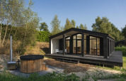Moderne tiny house 'The Hills' med sort facade, store vinduer, spabad og sauna ved Wilsumer Berge, Tyskland.