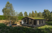Lille hus med grønt tag og stor terrasse, sauna og vildmarksbad ved Wilsumer Berge i Tyskland.