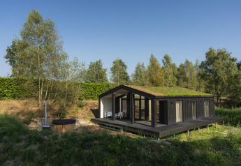 Lille hus med grønt tag og stor terrasse, sauna og vildmarksbad ved Wilsumer Berge i Tyskland.