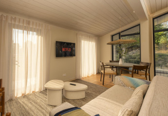 Lys stue i et tiny house ved The Hills, Wilsumer Berge, Tyskland, med sofa, spisebord og Netflix-TV.