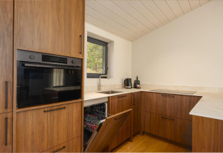 Cocina moderna en la tiny house The Hills en Wilsumer Berge, Alemania, con lavavajillas y horno integrado.