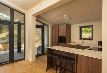 Moderne køkken i tiny house The Hills med store vinduer, træskabe og udsigt til natur ved Wilsumer Berge.