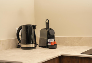 Black electric kettle and coffee pod machine on countertop in a tiny house at Wilsumer Berge, Germany.