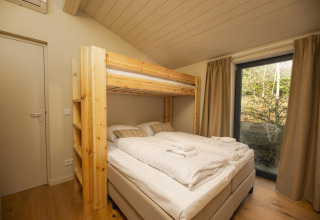 Dormitorio en The Hills tiny house con litera de madera, cama doble, ventana y vistas en Wilsumer Berge.